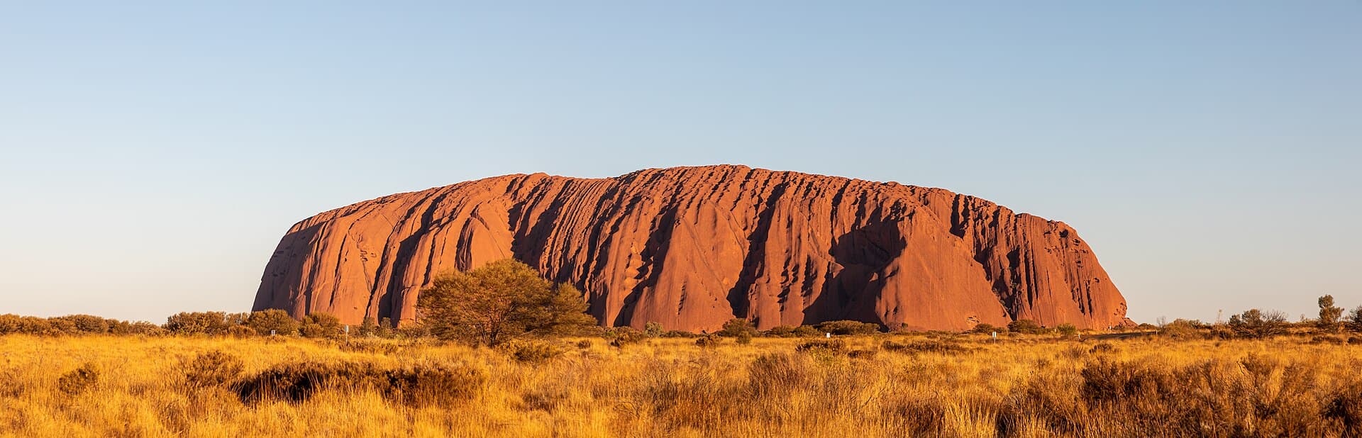 Uluru glowing orange at dusk across the Central Australian desert